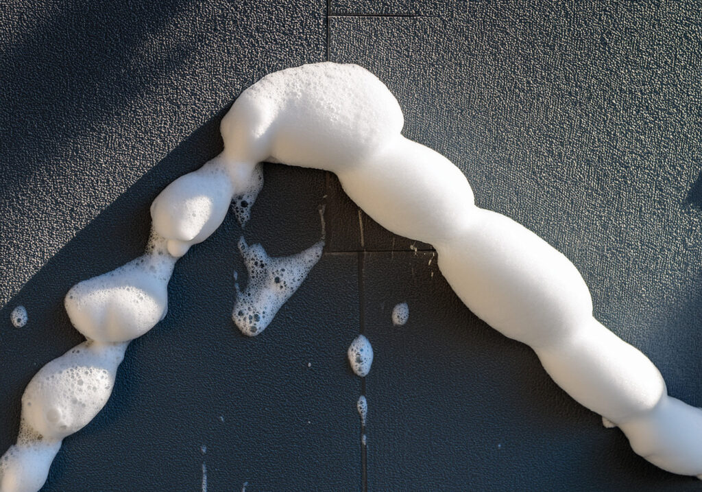 Close-up of professional biodegradable soft wash foam dwelling on a grey stucco facade, illustrating technical restoration for Glendale estates.