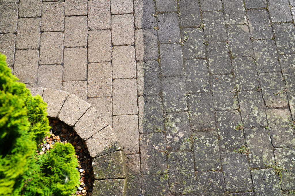 High-resolution top-down before and after restoration line on a stone paver walkway, demonstrating deep masonry cleaning by Flawless Facade.